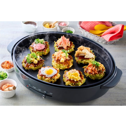Okonomiyaki på en varm stegepande – den klassiske japanske pandekage steges gylden og sprød med kål, toppings og den autentiske melblanding, som giver den perfekte konsistens og smag.