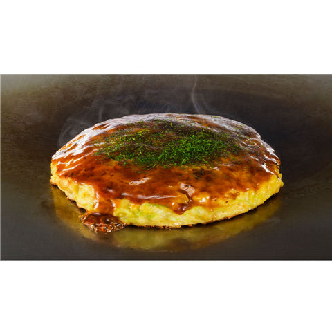 Okonomiyaki tilberedt på en japansk stegeplade – den traditionelle japanske pandekage steger på en varm teppan, hvor den udvikler sin sprøde overflade og saftige midte