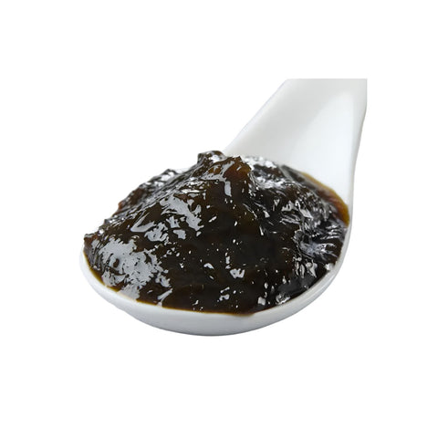 Tsukudani med wakame og nori tang på en japansk ske – den smukke, blanke tangdelikatesse med dyb mørkegrøn farve og intens umami. Den traditionelle japanske tsukudani er langsomt simret i sojasauce og mirin og er perfekt som topping til ris, sushi, onigiri, tofu og andre autentiske japanske retter.