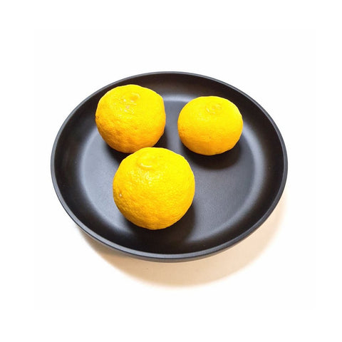 Japanske yuzu frugter på sort tallerken 